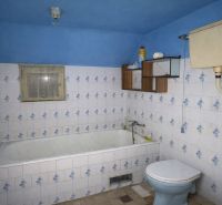 A bathroom in a family house with a blue bathtub, tiles, and a toilet.