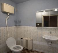 Bathroom with tiles, toilet, sink, and mirror in a family house.