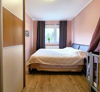 Bedroom with wood-patterned flooring, a bed, and a wardrobe in a 3-room apartment.