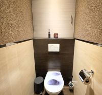 A bathroom in a three-room apartment with brown-beige tiles and a toilet.