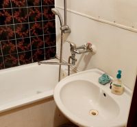 Bathroom with a bathtub, sink, and decorative tiles in a studio apartment.
