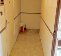 A narrow hallway in a one-room apartment with a tiled wall decor, light flooring.