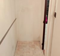 A narrow hallway in a studio apartment with white walls and patterned flooring.