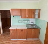 A kitchen in a studio apartment with tiles and wood-patterned flooring.