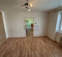 A room with a wooden floor design, a radiator, and a door to the kitchen in a studio apartment.