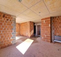 Unfinished interior of a 3-room apartment with brick walls and concrete floor.