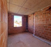 The interior of an unfinished 3-room apartment with brick walls and an opening for a window.