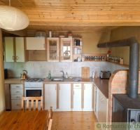 A kitchen in a family house with a rustic tiled stove and a wooden-patterned floor.