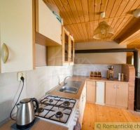 A kitchen with wooden decor in a family house with a gas stove and a wooden ceiling.