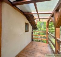 A wooden terrace of a family house in Cinobana surrounded by greenery and forest.