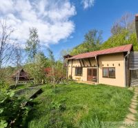 A family house in Cinobana surrounded by greenery, with a lawn and wooden terraces.