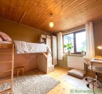 Children's room in a family house with a high bed and a desk by the window.