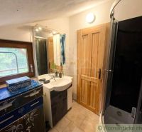 Bathroom with a sink, shower, and window, decorated cabinet, light walls.