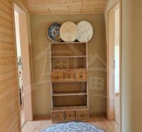 Interior of a family house with wooden walls, carpet, and a shelf with decorative bowls.