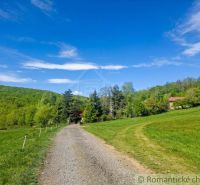 The path leads to a family house in Cinobana, surrounded by greenery and a blue sky.