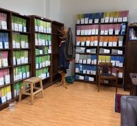 Shelving units full of binders in an office with a wood-patterned floor.