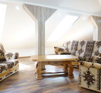 Attic living room of a 4-room apartment with comfortable armchairs and a wooden decor floor.