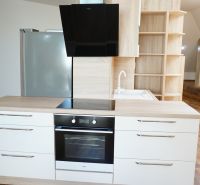 A kitchen in a 4-room apartment with a wood-patterned floor, built-in appliances, and storage spaces.