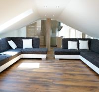 Attic living room in a 4-room apartment with sofas and a wooden decor floor.