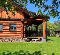 A wooden cottage surrounded by greenery in Piešťany with a well-maintained lawn and firewood.