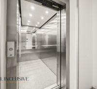 Elevator in a building with shiny metal walls and a lit ceiling, 2-room apartment.