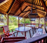 A wooden gazebo by the cottage in Nitra with seating among the trees.