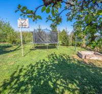 A garden by the cottage in Nitra with a trampoline, a basketball hoop, and a sandbox.