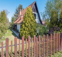 A cottage in Nitra surrounded by greenery with a wooden fence and a garden.