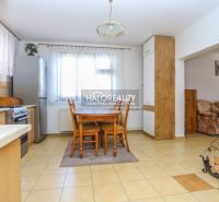 Freestanding kitchen with a dining table, wood-patterned flooring, and access to the living room.