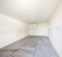 An empty room in a family house with cracked walls and a concrete floor.