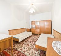A room in a family house with carpet, wooden furniture, and two beds.