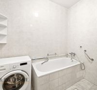 A bathroom in a family house with a bathtub, sink, and washing machine.