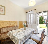 Dining room with a floral tablecloth in a family house, open doors to the garden.