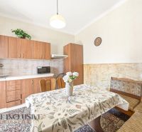 A kitchen in a family house with a kitchen unit, a dining table, and a patterned tablecloth.
