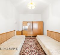 A room in a family house with two beds, a vintage cabinet, and a floral carpet.