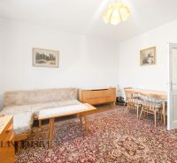 Living room in a family house with carpets, a sofa, paintings, and wooden furniture.