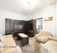 Living room with dark furniture and a floral carpet in a family house.
