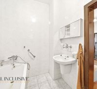 A bathroom in a family house with a bathtub and a sink, white tiles, access to the room.