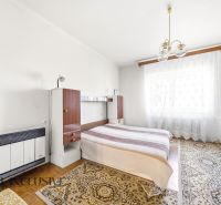 Bedroom in a family house with a bed, wardrobe, and carpets on a floor with a wooden decor.