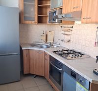 A kitchen in a 2-room apartment with a wooden decor and white appliances.