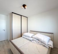 A bedroom in a two-room apartment with a wooden decor floor and a built-in wardrobe.