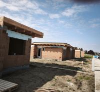 Construction of a family house on the street in Čierny Brod with cars in the parking lot.