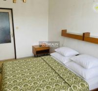A bedroom with a double bed in a 3-room apartment, nightstand, white wall.