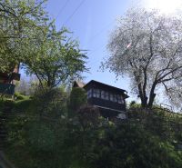 A cottage in a blooming garden in Zvolen, surrounded by trees and greenery.