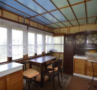 Interior of a garden with a dining table and cabinets, sunny environment through the windows.