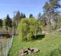 Gardens in Zvolen with plenty of greenery, trees, and a small wooden cottage.