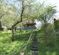 The staircase leads through a grassy garden in the city of Zvolen, surrounded by trees and shrubs.