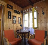Wooden wall paneling in the Gardens with decorations and two chairs by the table.
