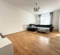 Living room in a three-room apartment with a wooden decor floor and a large sofa.