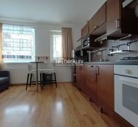 A kitchen in a 2-room apartment with a wooden decor floor and a dining area.